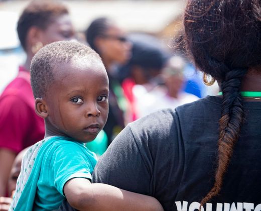Criança acolhida no colo durante atendimento humanitário