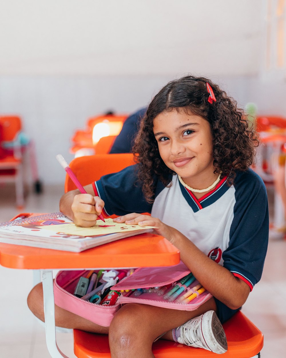 Menina desenhando na carteira da sala de aula