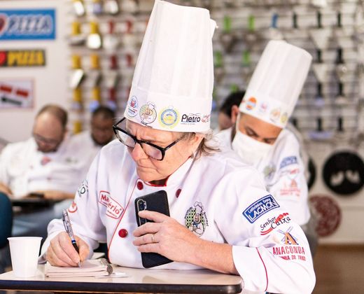 Crianças em aula prática de gastronomia, de chapéu de cozinheiro
