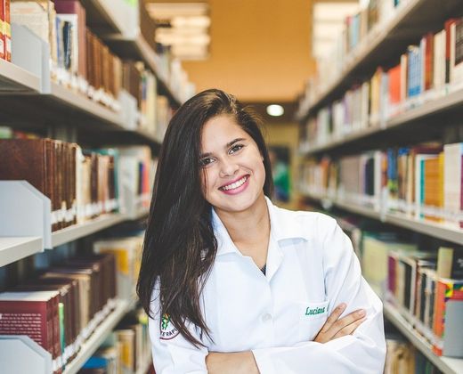 Estudante sorridente entre as estantes da biblioteca