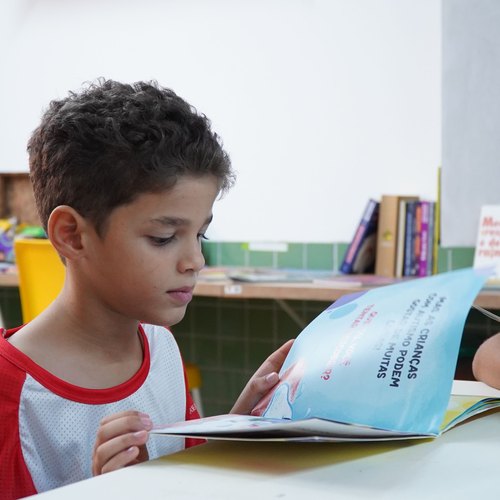 Menino de uniforme lendo um livro