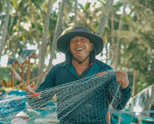 Pescador sorrindo com a rede de pesca artesanal