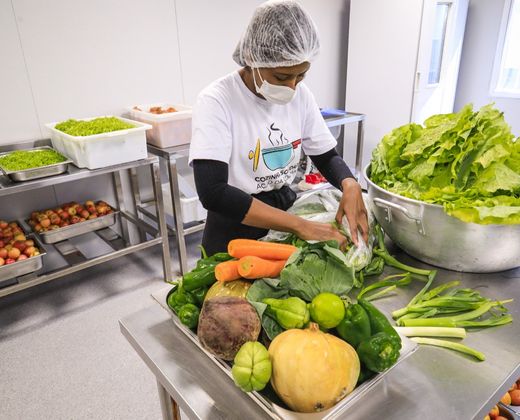 Voluntária preparando refeições em cozinha solidária