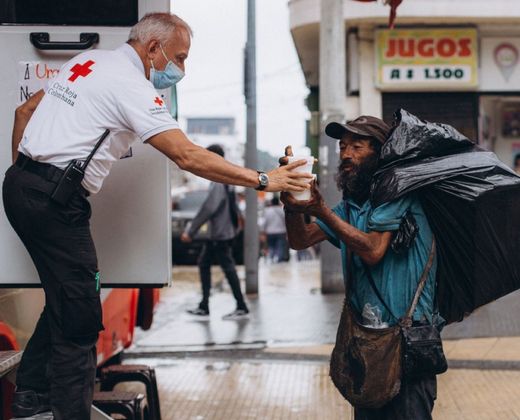 Voluntário entregando alimento a pessoa em situação de rua