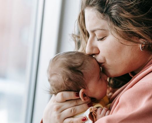 Mãe beijando o recém-nascido no colo