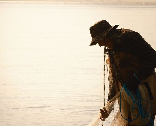 Pescador artesanal lançando a rede ao entardecer