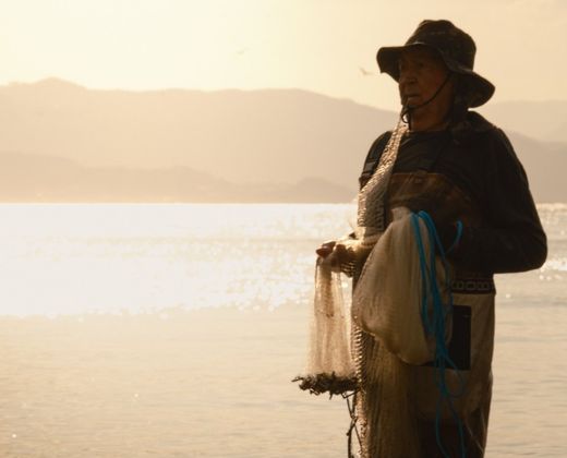 Pescador artesanal com a rede à beira da água
