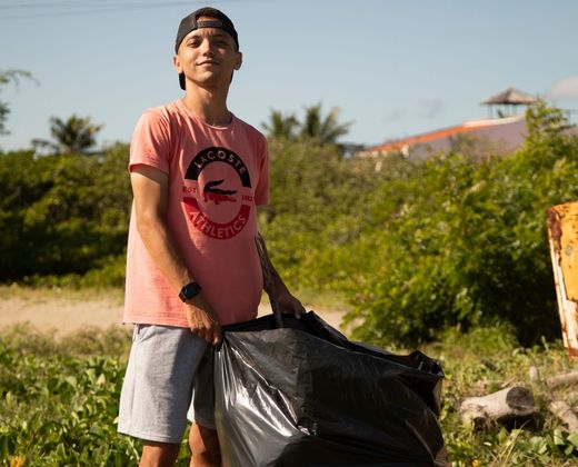 Voluntário recolhendo lixo em mutirão de limpeza