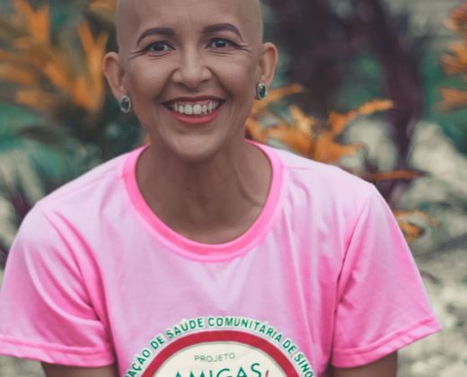 Mulher em tratamento oncológico sorrindo, camiseta de projeto de saúde comunitária