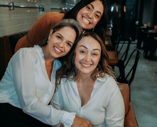 Três mulheres de gerações diferentes juntas e sorridentes