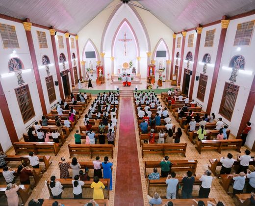 Interior de igreja com nave e bancos durante celebração